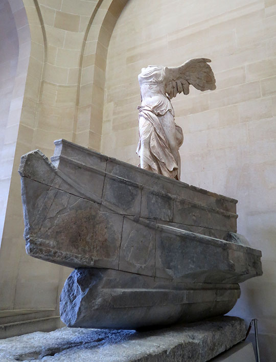 　跟著是羅浮宮的三寶之二的「薩莫色雷斯的勝利女神(Winged Victory of Samothrace ／ Nike of Samothrace) 」，是希臘神話中勝利女神尼克(Nike)的雕塑，創作於約公元前2世紀，自1884年起開始在羅浮宮的顯赫位置展出，是世界上最為著名的雕塑之一。藝術史家詹森(H.W. Janson)形容她為「希臘雕塑最偉大的傑作」，同時她也是現存為數不多的主要希臘原始雕像，而非羅馬複製品。<br /> <br />　勝利女神像高2.44米，她不僅表達了對勝利女神尼克的崇拜，更是一場海戰的象徵。她代表著戰鬥與勝利，衣裙迎風飄揚，仿佛女神從天而降，落在戰艦的船頭。勝利女神像的出色之處在於將動態的動作與突然間的靜止融為一體，女神保持著優雅平衡的身姿，垂下的衣裙在強勁海風中隨風擺動。